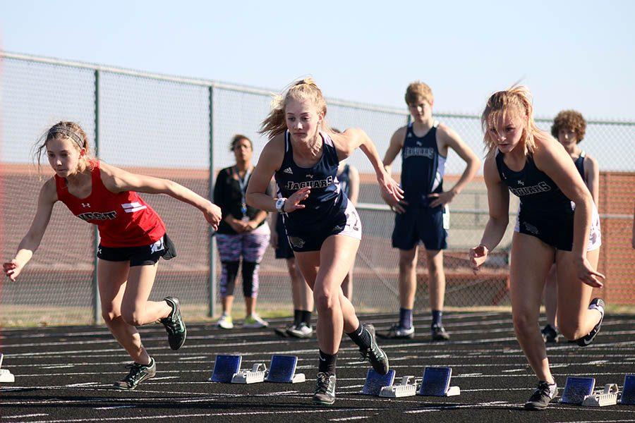 During the 100 meter dash, freshmen Khloe Knernschield (middle) and Megan Walkup (right) push off of their blocks at Blue Valley West on Thursday, March 23.