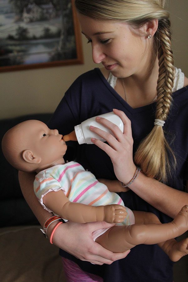  Feeding the baby in her arms, senior Sarah Butler works on her Human Growth and Development project at home on Sunday, Feb. 5. “I learned that babies are a lot more work than you’d think,” Butler said. “If it started crying, I would have to drop everything to take care of it; it was so unpredictable.” 