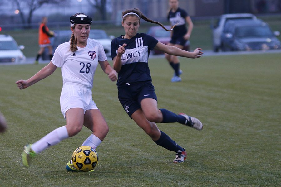 Pushing her opponent, junior Payge Bush battles for the ball during the game against Olathe North on Wednesday, March 29.