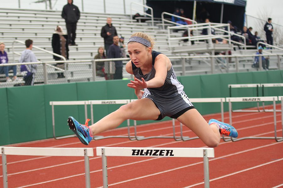 Reaching forward, freshman Mallory Scheelk jumps over a hurdle.