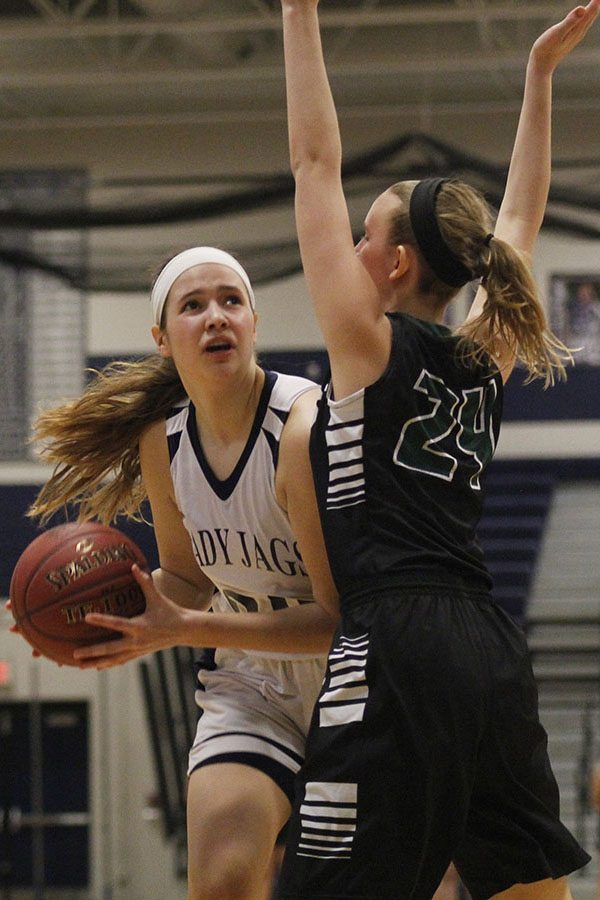 Preparing to shoot a basket, sophomore Trinity Knapp avoids an opponent. 
