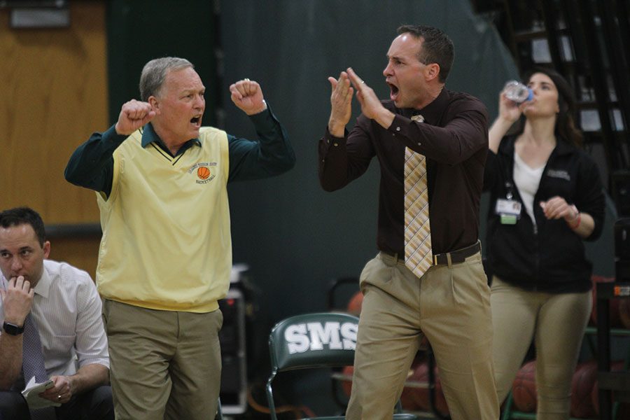 Alongside his son, Shawnee Mission South head basketball coach Brett McFall, retiree John McFall assists with coaching the boys varsity basketball team on Tuesday, Feb. 21. 