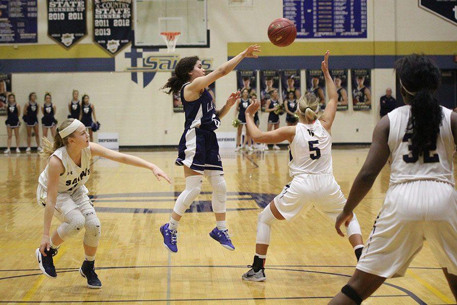 Passing, sophomore Presley Barton leaps above the court.