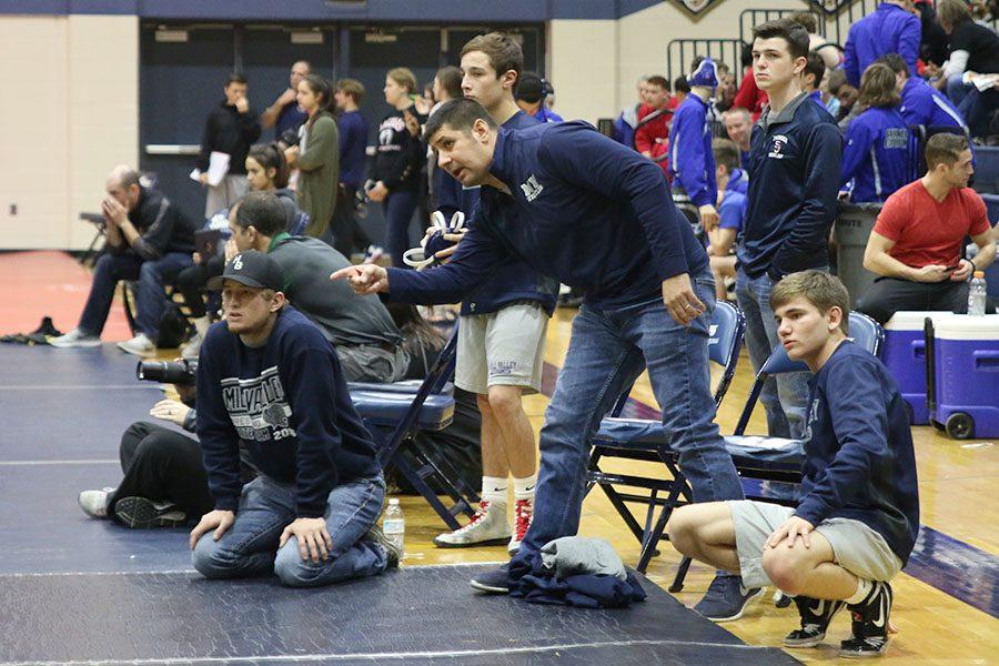 During an intense wrestling match, head coach Travis Keal stands to direct a 
wrestler to assist them in winning their match on Saturday, Feb. 11.