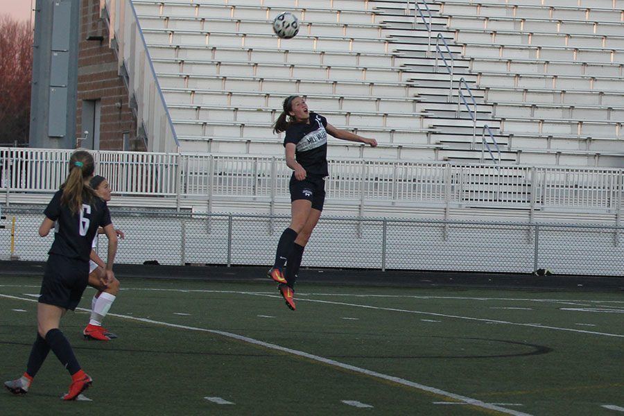 Jumping in the air, freshman Lanie Whitehill does a header.