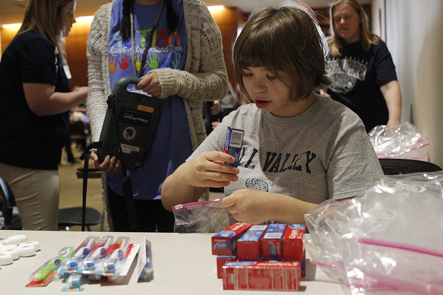 Senior Julie Burke places toothpaste in a plastic bag during the bag stuffing competition on Thursday, April 13.