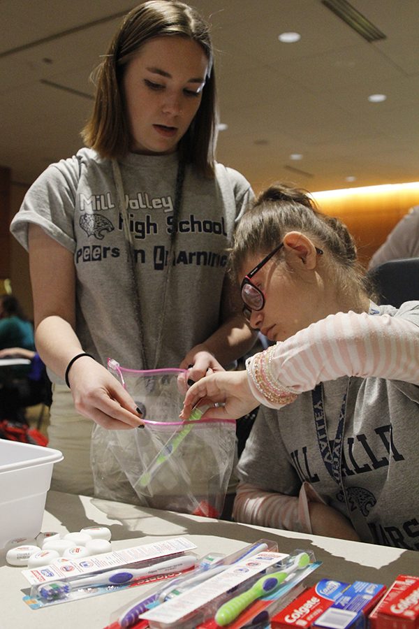 Junior Dakota Wilson assists sophomore Corinne Brown in the bag stuffing event.