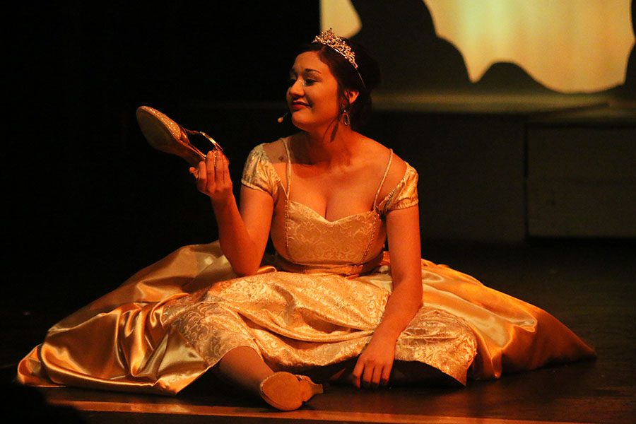 Cinderella, played by senior Natalie Carrera, looks at her golden slipper.