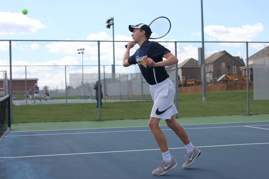 Pushing forward to return the ball, junior Eric Schulz readies to swing.