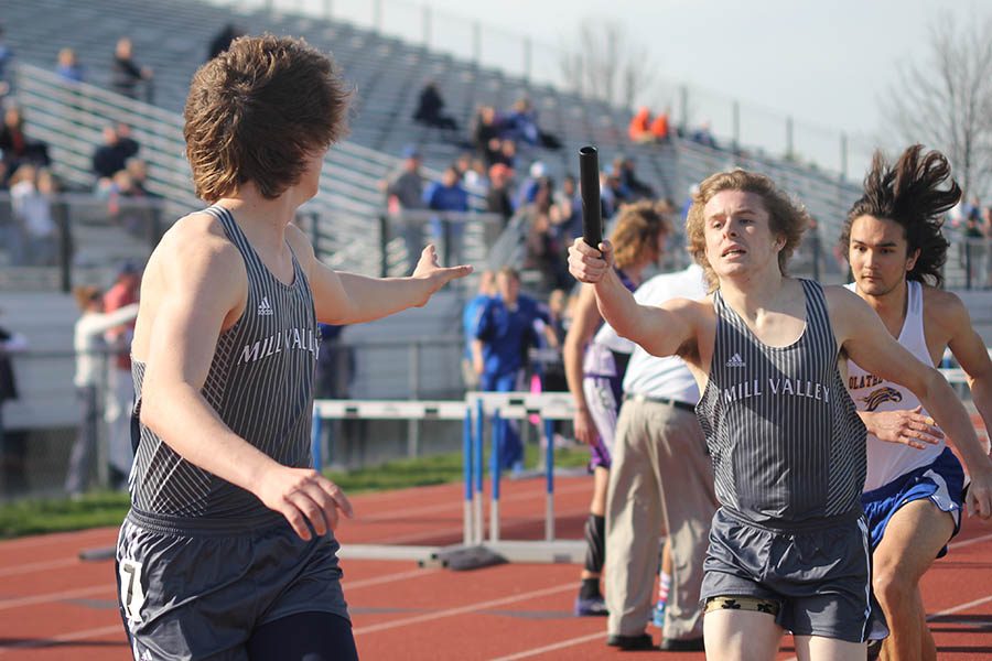 Handing off the baton, senior Riley Arthur pushes for junior Mitch Dervin to take it.