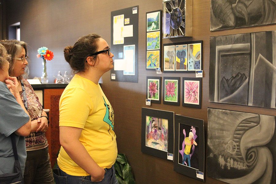 Attending the Country Club Bank art show opening on April 24th, senior Meghan Clark looks at artwork created by Mill Valley students.