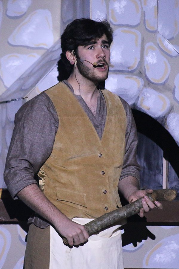 The Baker, played by junior Simon Stewart, sings during the opening while holding a log from his stove.
