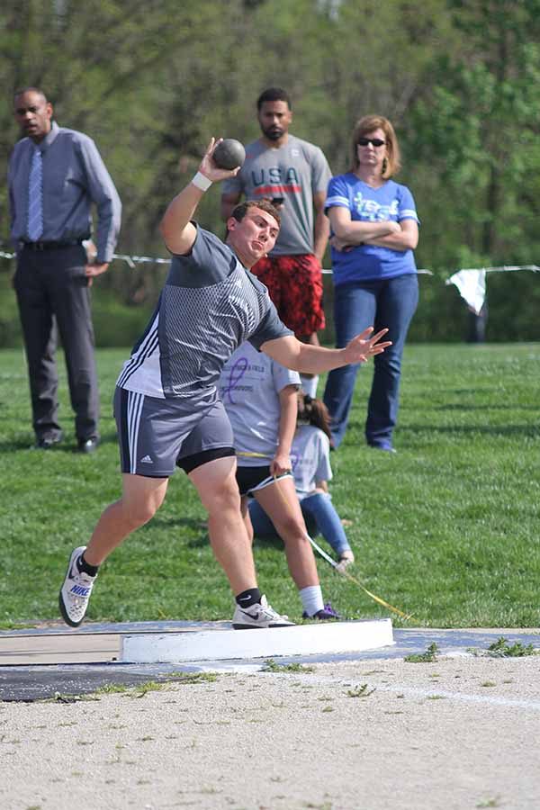 Leaning forward, sophomore Christian Roth thrusts the shot-put ball.