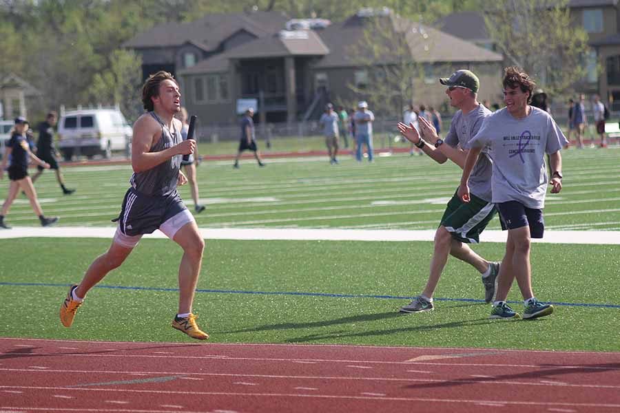 With junior Justin Grega cheering him on, senior Thomas Hopkins runs in the 4 by 8 relay event.