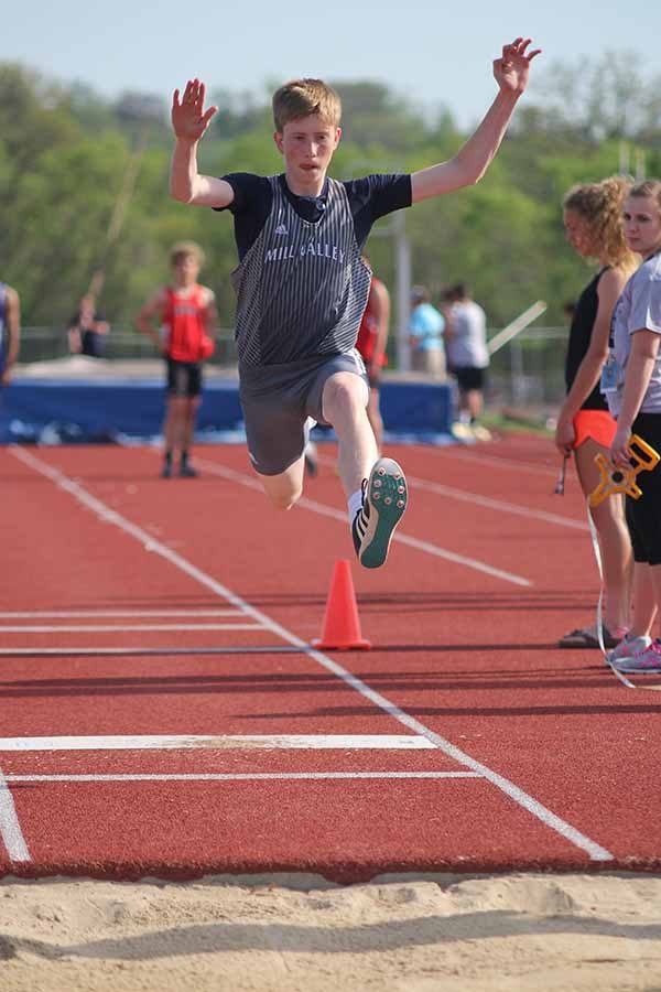 With arms in the air, sophomore Harry Ahrenholtz leaps into the sand pit.