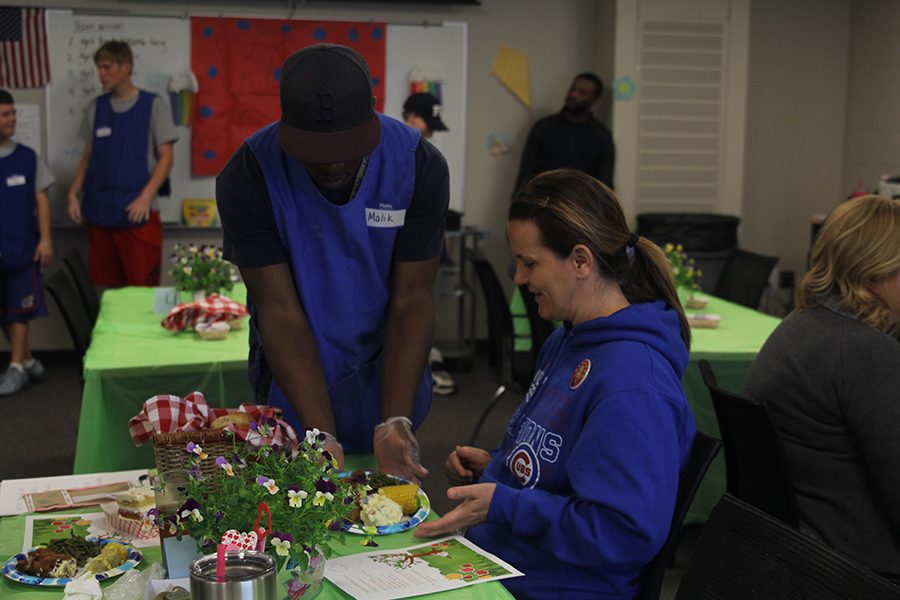 Junior Malik Redmond serves physical education teacher Amy McClure her food.