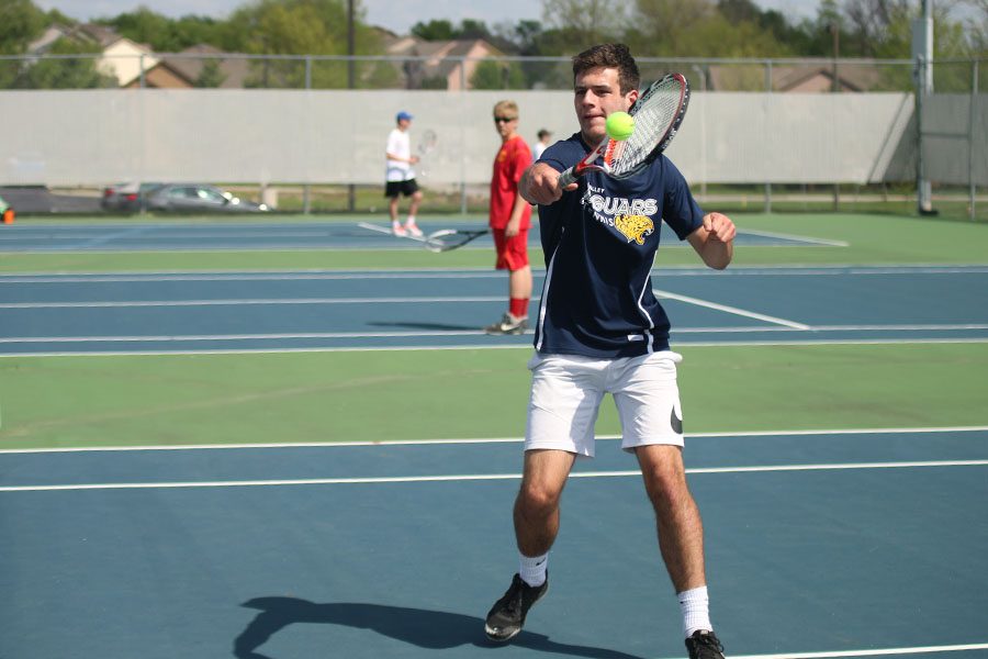 Following through on his swing, junior Bradley Teasley hits the ball over the net towards his opponent. 