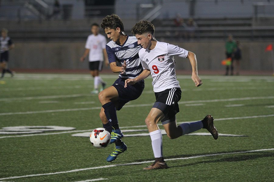 Fighting for the ball, senior Adam Grube blocks a Shawnee Mission North player on Tuesday, Aug. 30. The Jaguars won after the game was called at halftime due to inclimate weather, making the final score 4-0. 
