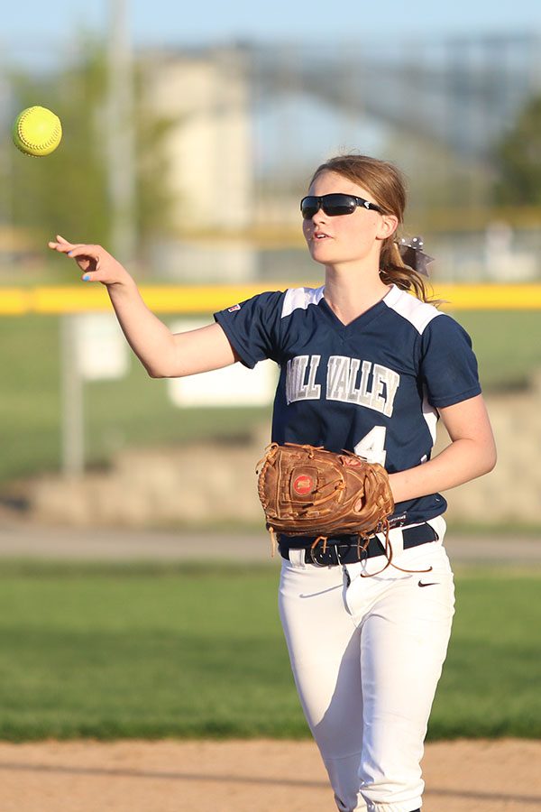 Between innings, junior Sydney Parker throws the ball to a teammate.