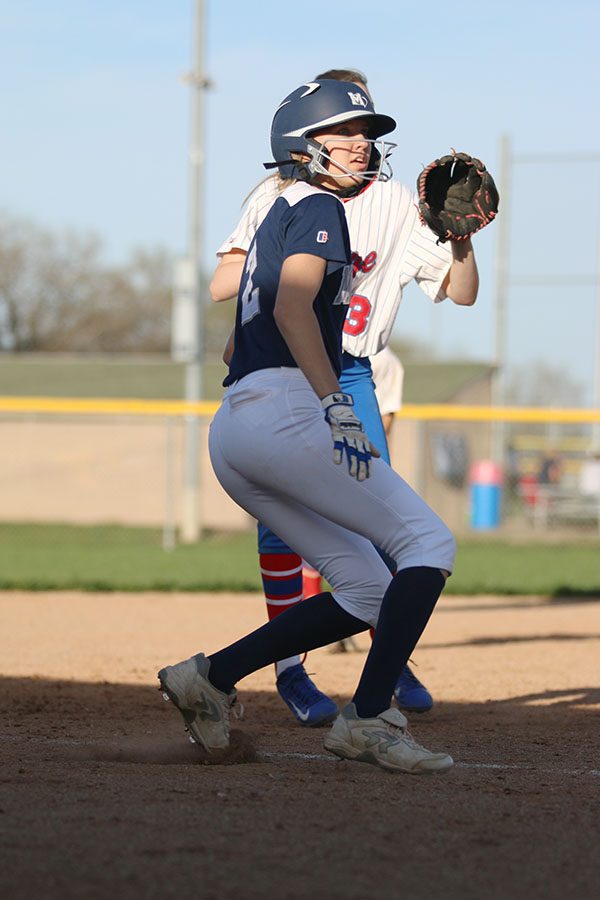 Watching the ball, junior Lilly Blecha prepares to slide onto third base.