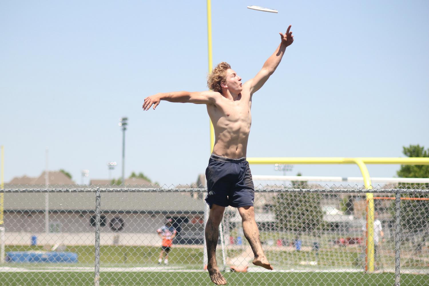 Senior Jack Eber jumps for a frisbee while waiting to play his set at the mud volleyball tournament.