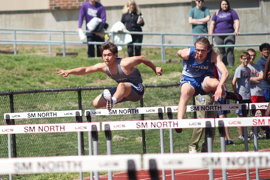 With arms stretched out, junior Eli Midyett leaps over the first hurdle.