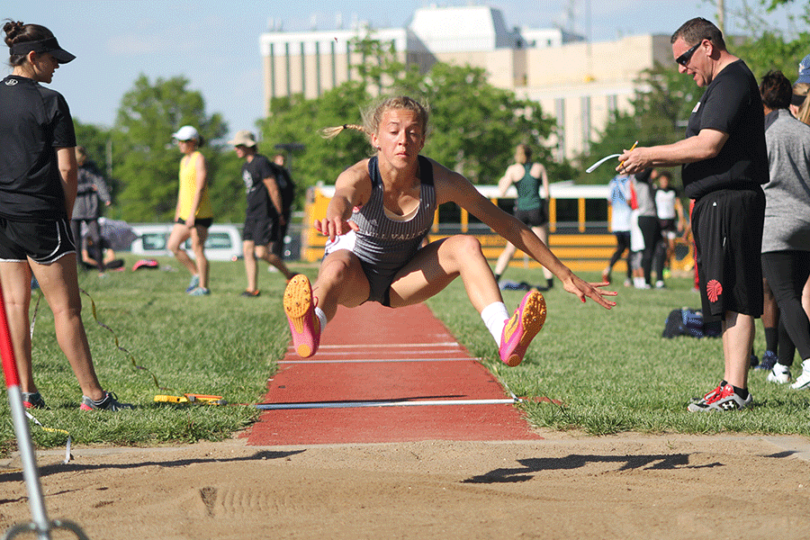 In the long jump, senior Morgan Thomas reaches forward before landing in the sand pit on Friday, May 5 at Shawnee Mission North.