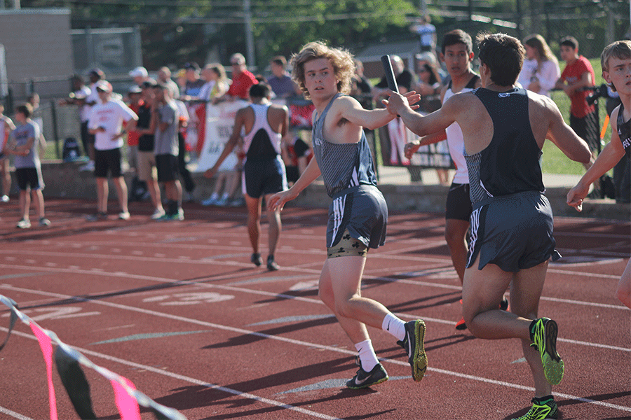 Looking back, senior Riley Arthur reaches for the baton from junior Justin Grega.