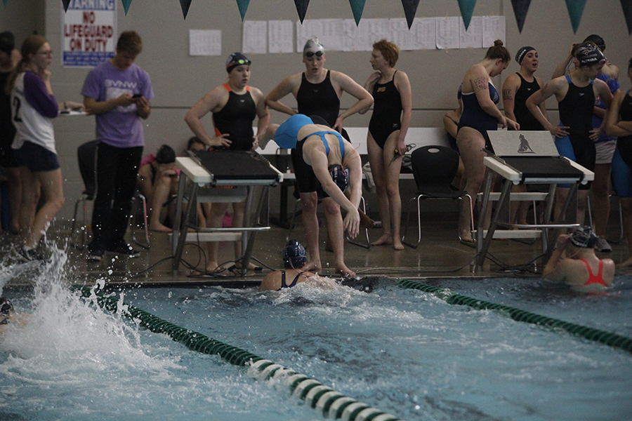 Freshman Alison Godfrey dives into the water after her teammate sophomore Celia Kistner touches the wall.