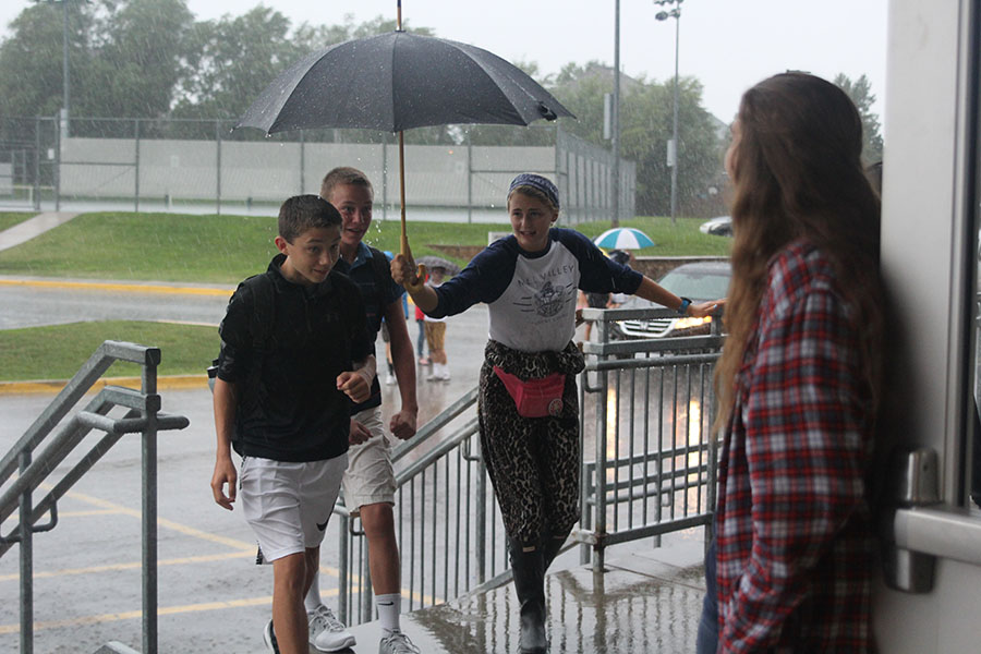 To keep off the rain, senior student body president Bella Hadden holds an umbrella as she welcomes two freshmen. 