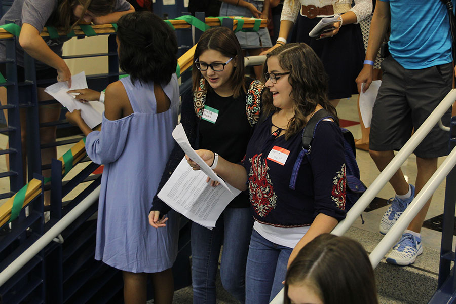 Walking down the main stairs, two freshmen look at their schedules to find their classes. 