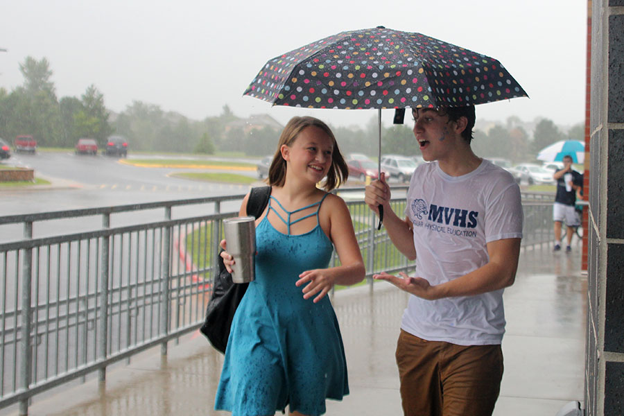 Despite the rain, freshman Avery Hansford laughs as she is escorted into the building at freshman orientation on Wednesday, Aug. 16.