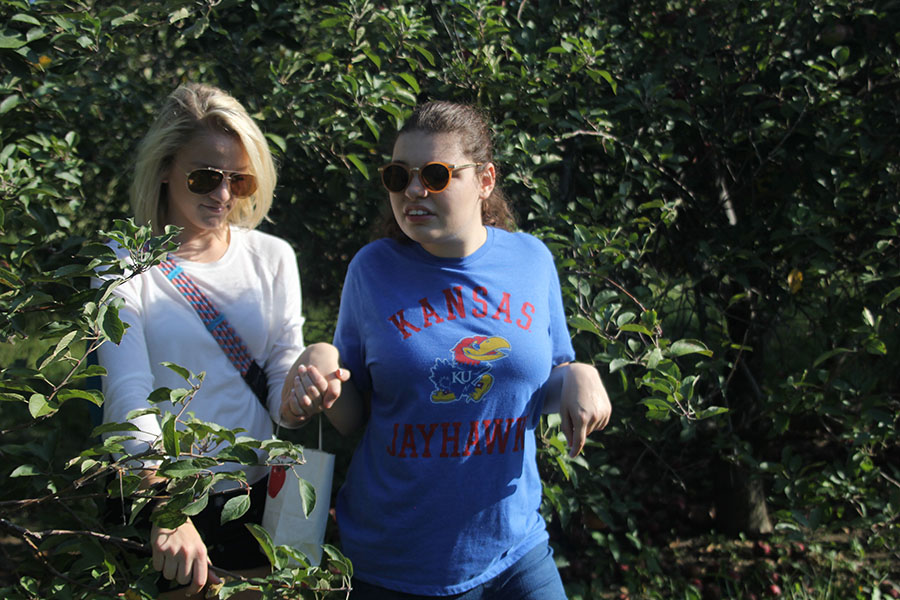 Senior Abby Debrabander walks through trees with junior Bella Line in hand.