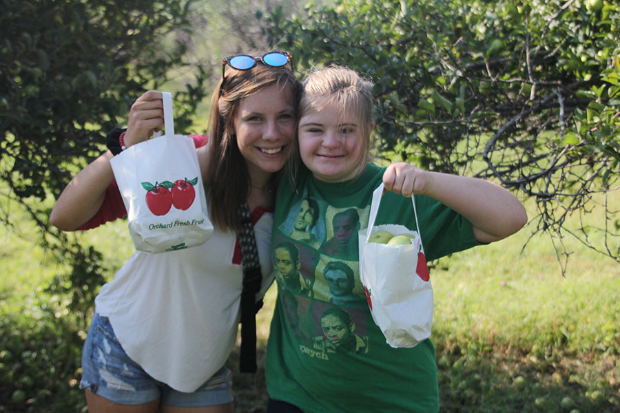 Sophomore Maria McElwee shows off her bag full of apples with junior Madi Reishus.