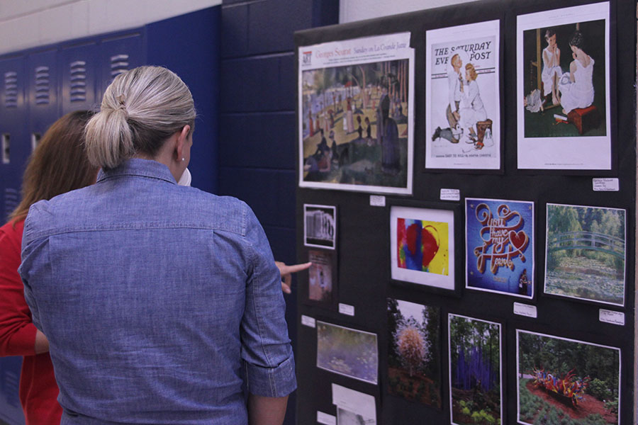 Teachers look and admire the art projects made by students.