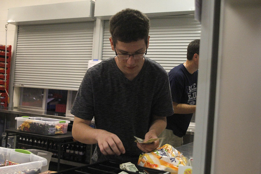 While counting bills on Friday, Sept. 8, junior Tyler Hilk helps a customer at the concessions stand.
