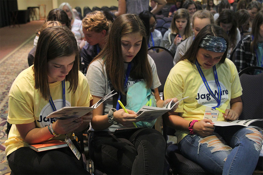 Juniors Annie Myers, Sophie Friesen and Marah Shulda look at their conference guides for session information.
