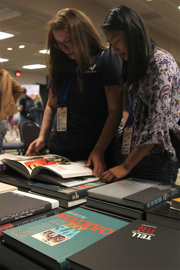 Juniors Mia Thomas and Libby Mullican view other schools yearbooks in the convention trade show.