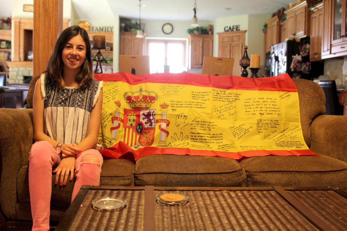While in her host family's house, foreign exchange student and senior Elena Ortega Camazón poses in front of the Spanish flag signed by her family on Monday, Sept. 11.