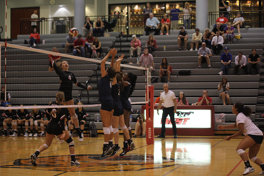 The front row of hitters jumps up to block a ball.