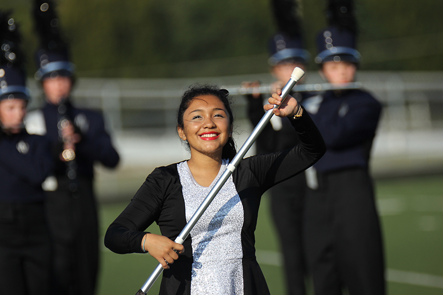 Senior Sofia Torres-Aranda smiles at the crowd while twirling her flag getting ready for the next motion. 