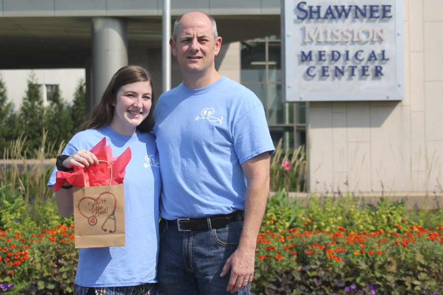 Alongside her dad, and hero, Dan Tennis, senior Aly Tennis holds a care package she created for on-duty nicu nurses outside of Shawnee Mission Medical Center. On Friday, Sept. 15 she plans to deliver the packages containing “granola bars, coffee, gum, scrunchies, tissue paper, and syringe pens,”  the essentials for a long shift.