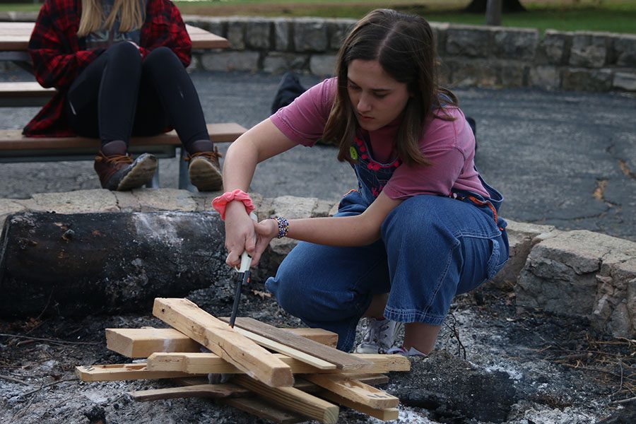 To start the bonfire, junior Hannah Barnes lights the plywood.