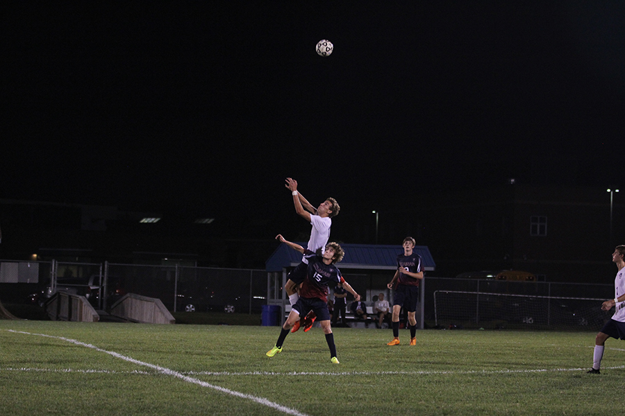 Junior Jake Ashford leaps over Topeka Seaman player to get the header on Monday, Oct. 2.