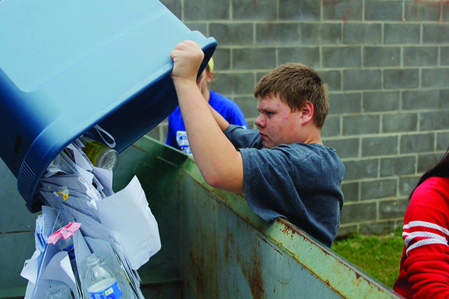 During the class' recycling round, sophomore Jared Brehaney empties the collected recycled items into the dumpster outside on Tuesday, Oct. 3.