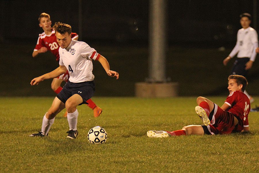 Moving the game down the field, senior Kyle Franklin dribbles the ball through a defender. 