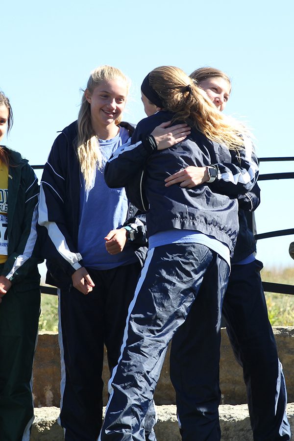 After receiving her 10th place medal, freshman Molly Ricker hugs senior Britton Nelson and freshman Josie Taylor while taking her place on the podium.