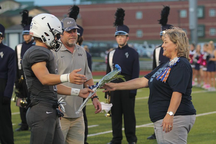 As he hands the flower to his mom, senior Evan Rice reaches out to give her a hug.
