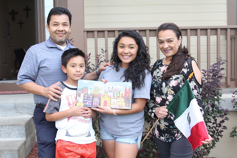 Surrounded by her family, senior Sofia Torres-Aranda displays a book that contains many parts of the Mexican culture, like the architecture, food and environment. 