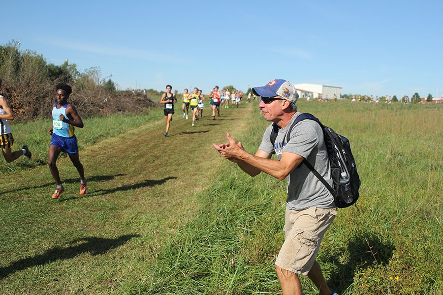 While on the course at Raymore-Peculiar High School, head coach Chris McAfee cheers on the varsity boy runners on Saturday, Sept. 30.